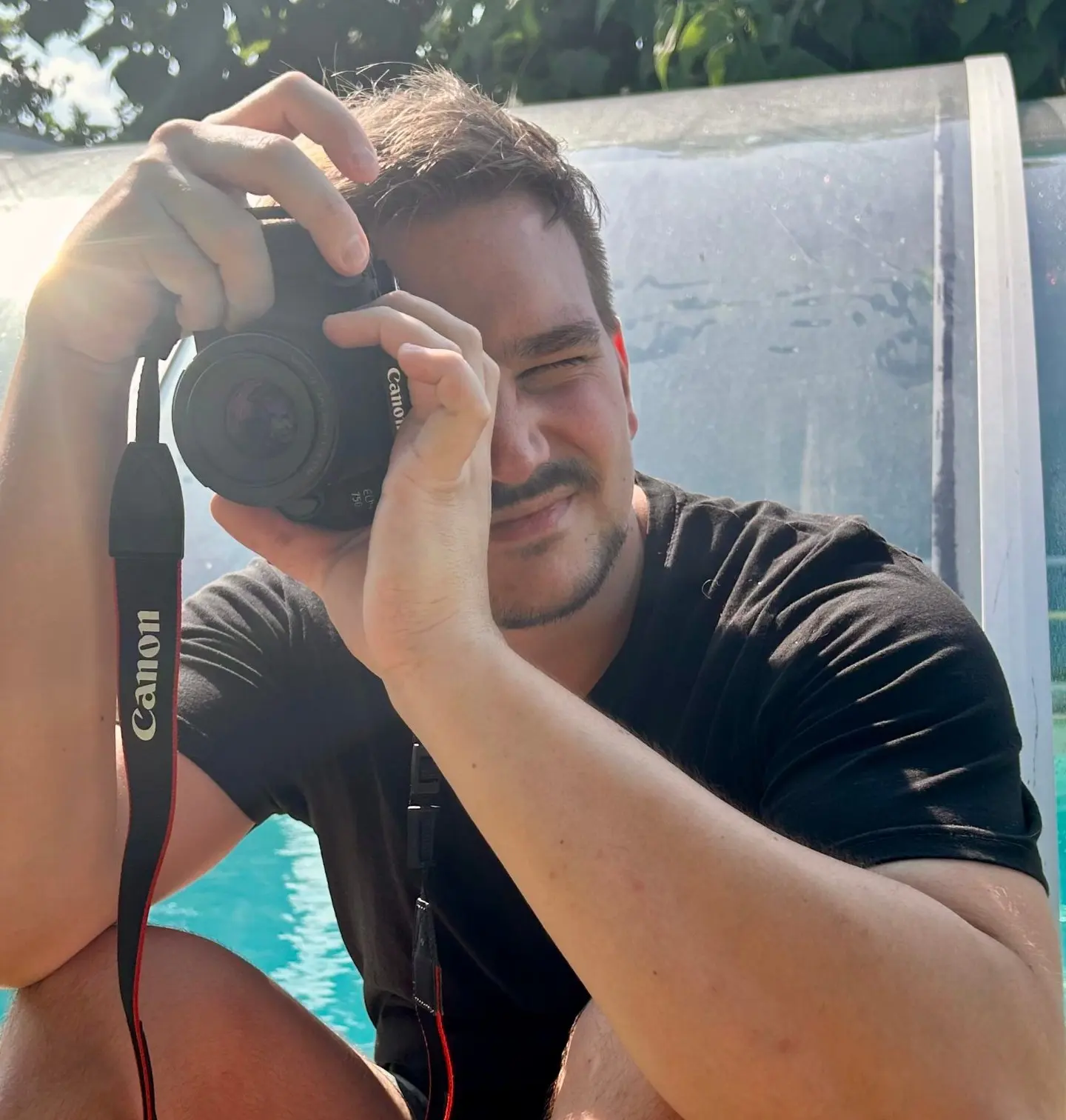 Christoph Suppan crouching by a pool, looking through the viewfinder of a camera
